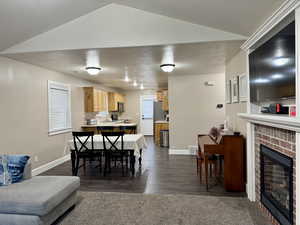 Dining area featuring a brick fireplace and dark wood-style flooring