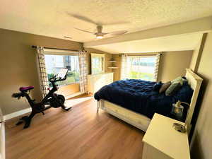 Bedroom featuring updated wood flooring, & large energy efficient windows.