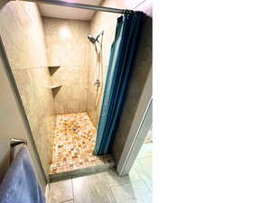 Updated bathroom with custom tile shower surround, and overhead shower faucet.