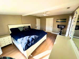 Bedroom featuring updated wood flooring, and a beamed ceiling.