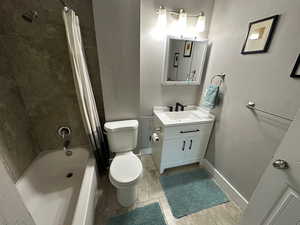 Bathroom featuring shower / tub combo, vanity, a textured wall, and light tile patterned floors