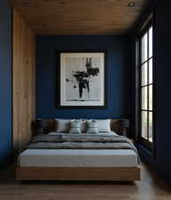 Bedroom with wooden ceiling, multiple windows, and wood finished floors