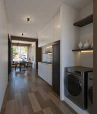 Laundry area with dark wood finished floors and separate washer and dryer