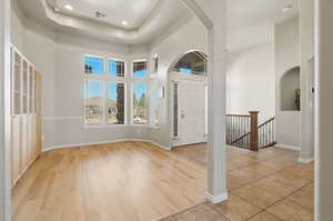 Entrance foyer featuring arched walkways, a high ceiling, recessed lighting, light wood finished floors, and a raised ceiling
