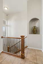 Corridor with an upstairs landing and light tile patterned flooring