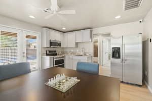 Kitchen with stainless steel appliances, white cabinetry, light wood-style flooring, recessed lighting, and a ceiling fan