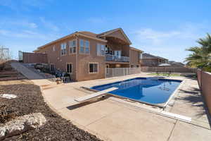 View of swimming pool with a balcony, a patio area, and a diving board