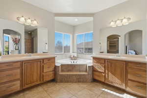 Bathroom with two vanities, a garden tub, light tile patterned flooring, ensuite bath, and a shower
