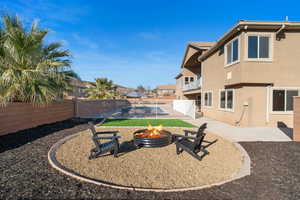 Fenced backyard featuring a patio area, a balcony, and a fire pit