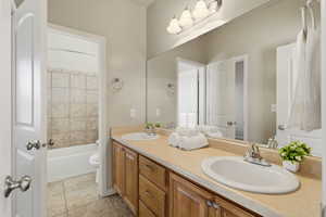Bathroom with double vanity, light tile patterned flooring, and a bath