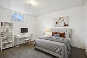 Carpeted bedroom with a textured ceiling and a desk