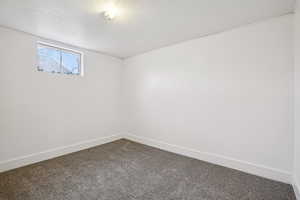 Carpeted empty room featuring a textured ceiling and baseboards