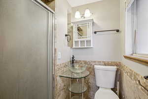 Bathroom featuring a wainscoted wall, tile walls, and a shower stall