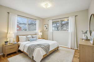 Bedroom with light wood-type flooring, multiple windows, and a textured ceiling