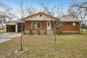 View of front of property with brick siding, driveway, a front yard, and a shingled roof