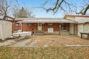 Rear view of house with brick siding, a patio, roof with shingles, and a porch