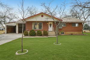 View of front of property with brick siding, driveway, and a front lawn