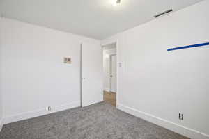 Carpeted empty room featuring baseboards and a textured ceiling