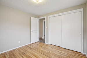 Unfurnished bedroom with a textured ceiling, a closet, and light wood-type flooring