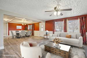 Living area featuring wood finished floors, plenty of natural light, a textured ceiling, a wainscoted wall, and a chandelier