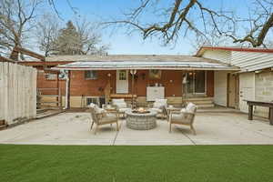 Rear view of property with a patio, brick siding, entry steps, and a fire pit