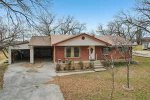 View of front of property with roof with shingles, covered porch, brick siding, and driveway