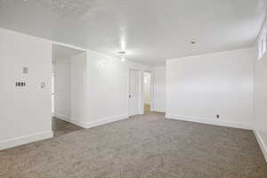 Empty room with carpet floors and a textured ceiling