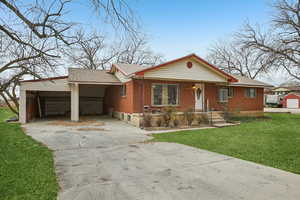 Ranch-style home with a front yard, concrete driveway, roof with shingles, a porch, and brick siding