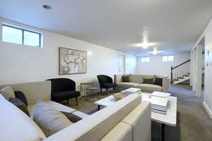 Living room with healthy amount of natural light, carpet, a textured ceiling, and stairway