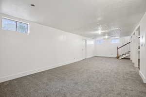 Below grade area featuring carpet, a textured ceiling, and stairs