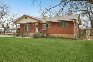 View of front of house with a front lawn, brick siding, and a chimney