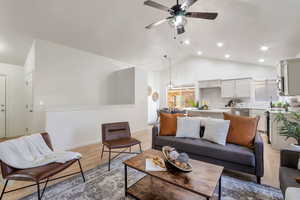Living area featuring light wood finished floors, ceiling fan, and high vaulted ceiling
