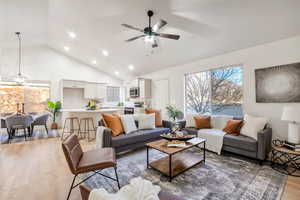 Living room with light wood-style flooring, high vaulted ceiling, recessed lighting, and a ceiling fan