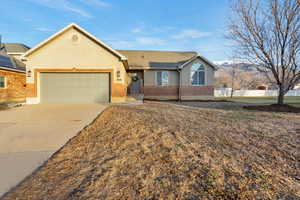 Ranch-style house featuring concrete driveway, a garage, brick siding, and stucco siding
