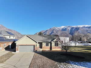 View of front facade featuring an attached garage, a mountain view, concrete driveway, brick siding, and stucco siding
