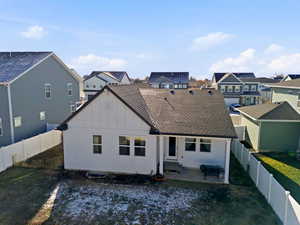 Rear view of house featuring board and batten siding, a patio, a fenced backyard, a residential view, and a shingled roof