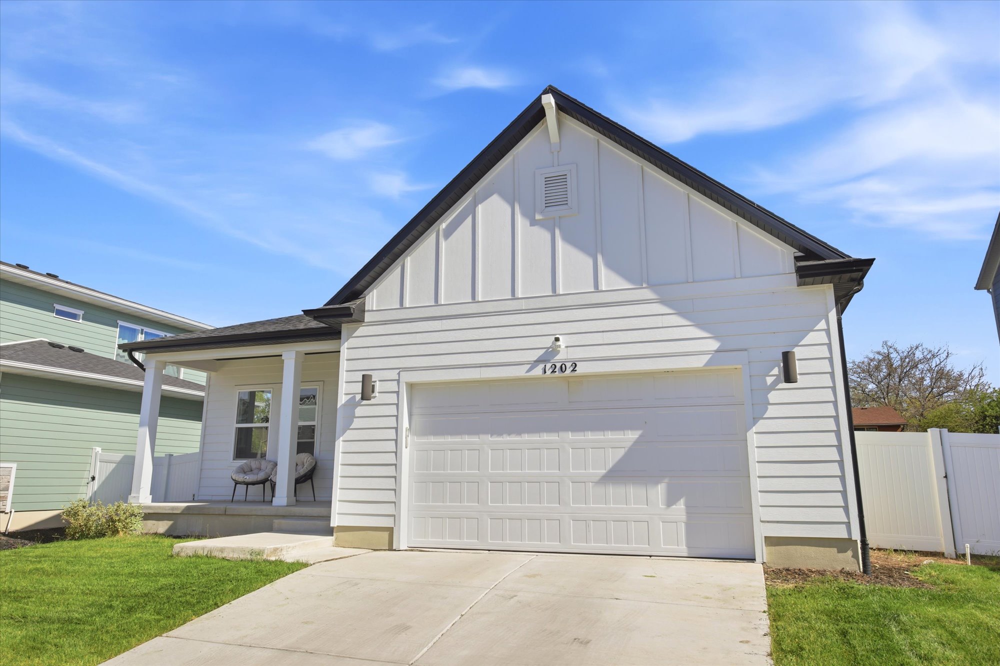 Contemporary single-story residence featuring white horizontal siding and board and batten gables