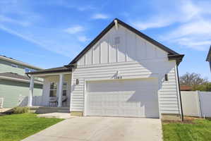 Contemporary single-story residence featuring white horizontal siding and board and batten gables