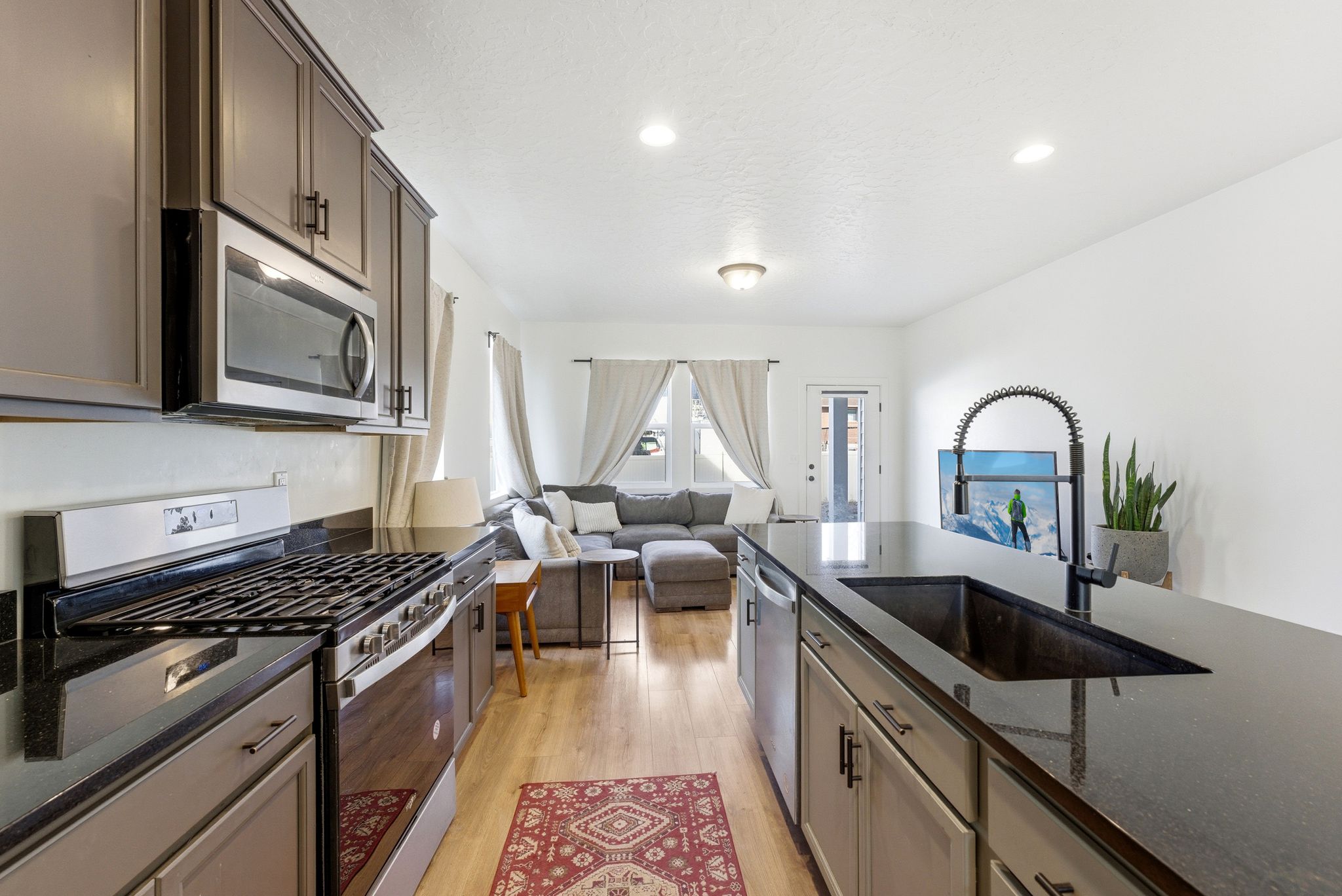 Kitchen featuring appliances with stainless steel finishes, dark stone counters, open floor plan, light wood-style floors, and recessed lighting