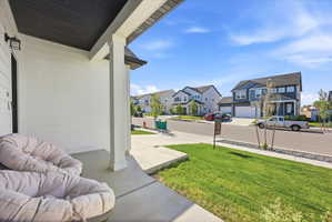 Covered front porch with white siding, dark soffit, and a traditional exterior light fixture