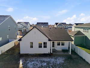 Rear view of house featuring board and batten siding, a fenced backyard, a patio, and a residential view