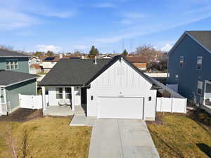 View of front facade featuring board and batten siding, a porch, concrete driveway, an attached garage, and a gate