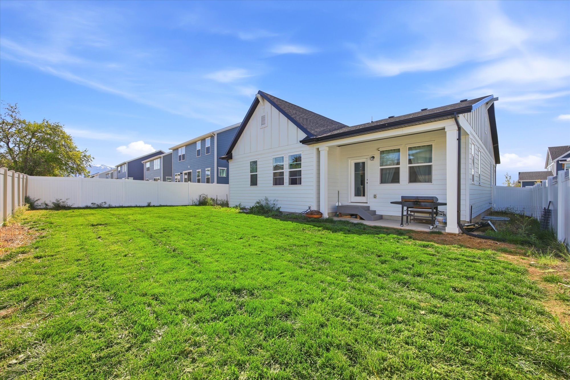Expansive green lawn with a white vinyl privacy fence