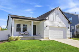 Modern farmhouse exterior featuring white horizontal siding, a prominent gable roofline, an attached single-car garage, and a covered front porch with white columns