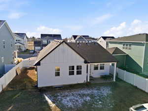 Rear view of house with board and batten siding, a fenced backyard, a patio, and a residential view