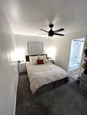 Bedroom with dark carpet, ceiling fan, and ensuite bath