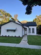 Ranch-style house with stucco siding and a front yard