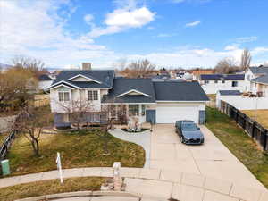 Split level home featuring concrete driveway, a garage, a residential view, and roof with shingles