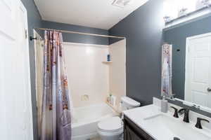 Full bathroom featuring vanity, shower / bath combo with shower curtain, and a textured ceiling