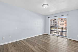 Unfurnished room with a textured ceiling and wood finished floors